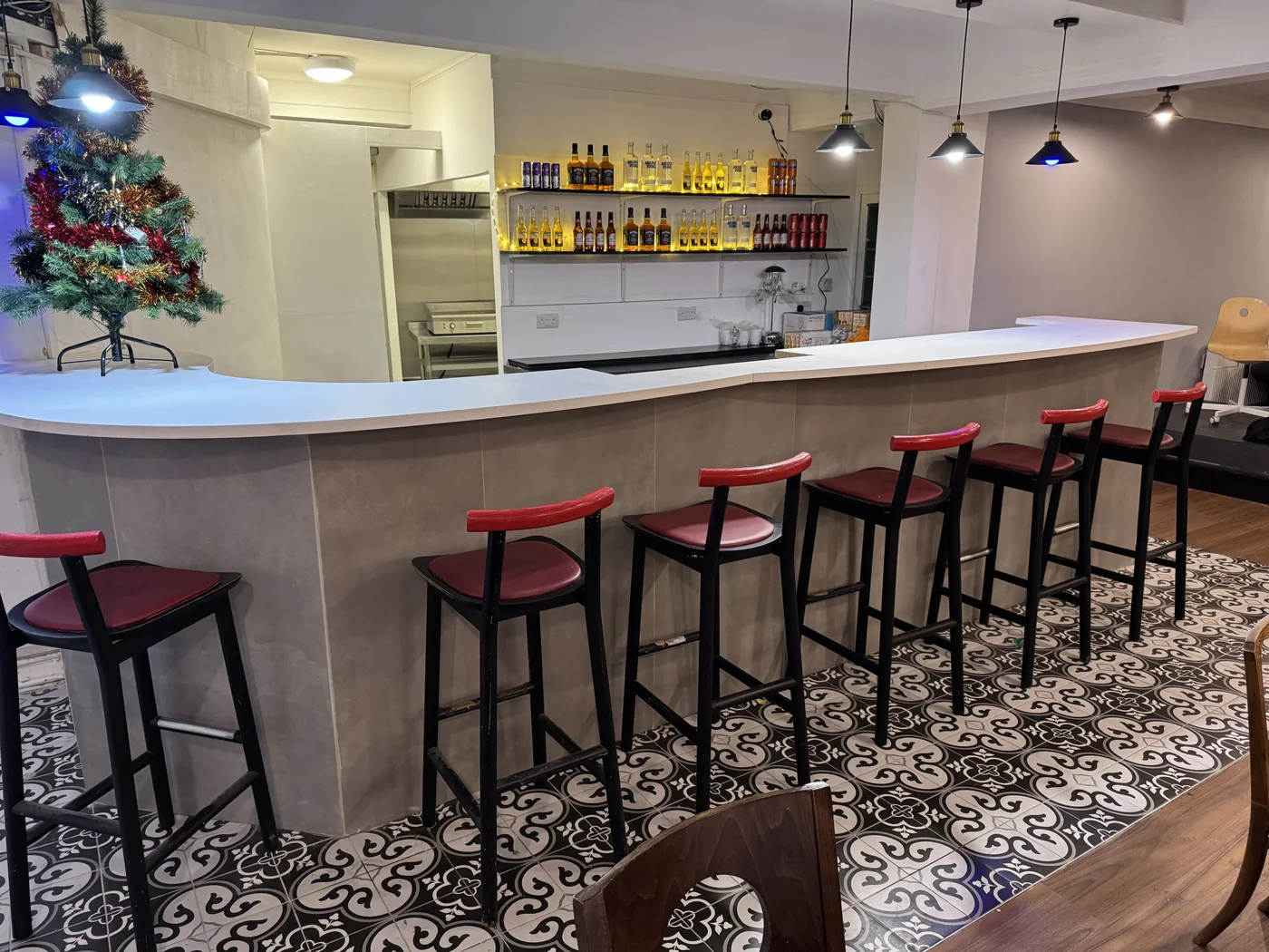 Last Tango's long pale bar with burgundy stools, pendant lights and patterned floor tiles.